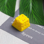 Yellow cheese keycap photographed beside a book | SIMPOCUBIC