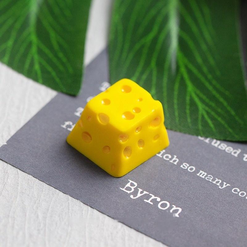 Yellow cheese keycap photographed beside a book | SIMPOCUBIC
