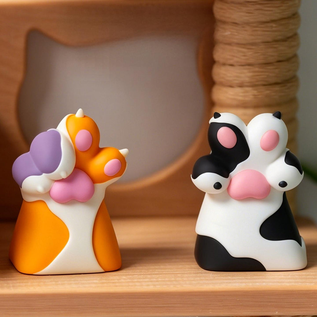 Cat and dog paw single keycaps displayed side by side on a tabletop